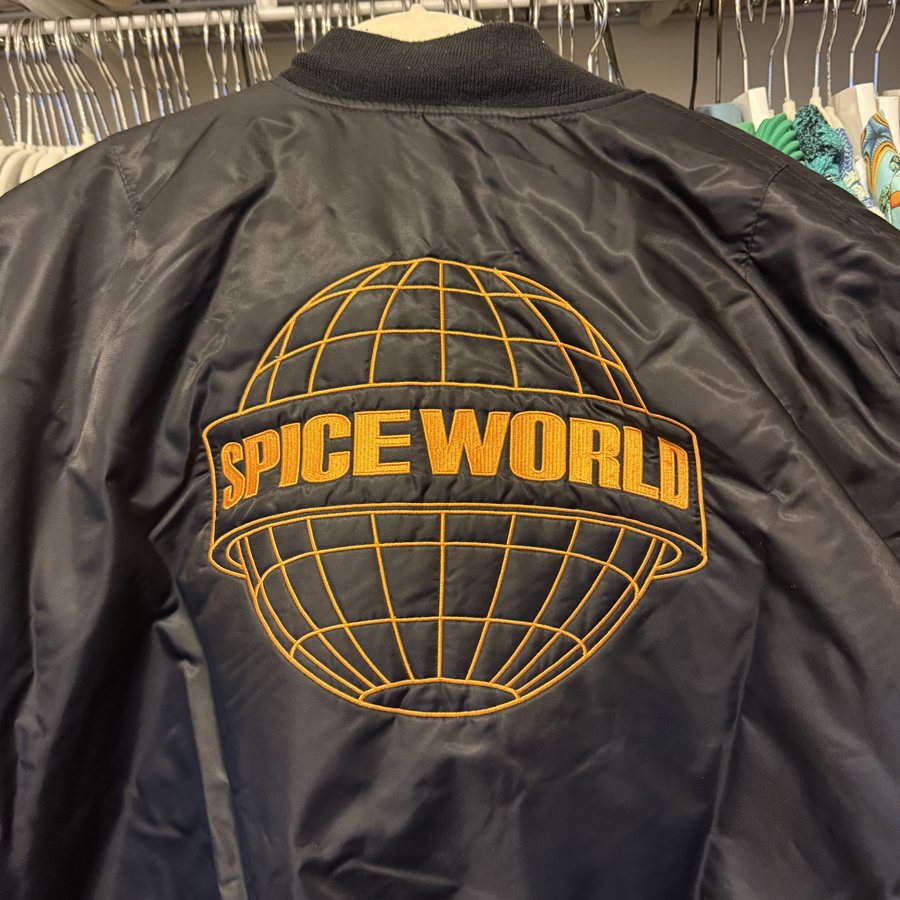 A black bomber jacket with a Spice World globe logo embroidered on the back