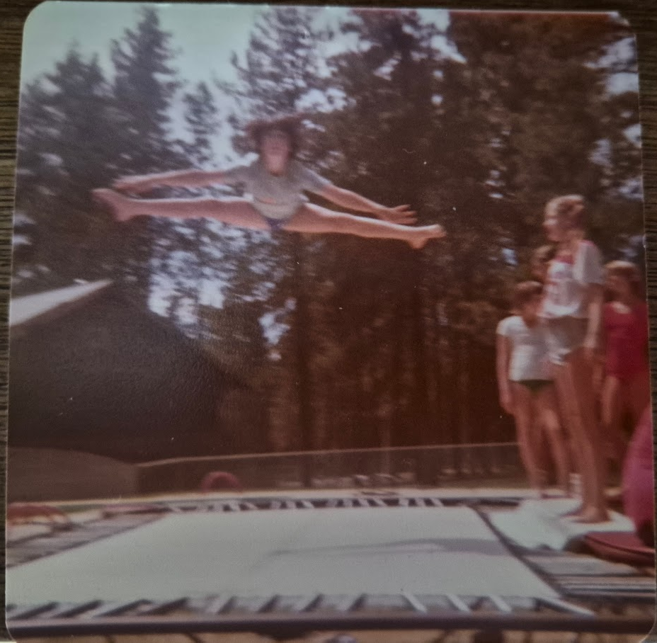 Wendy Jo as a kid mid-air on a trampoline doing a split jump in a wide-brimmed hat, with other kids watching from the side.